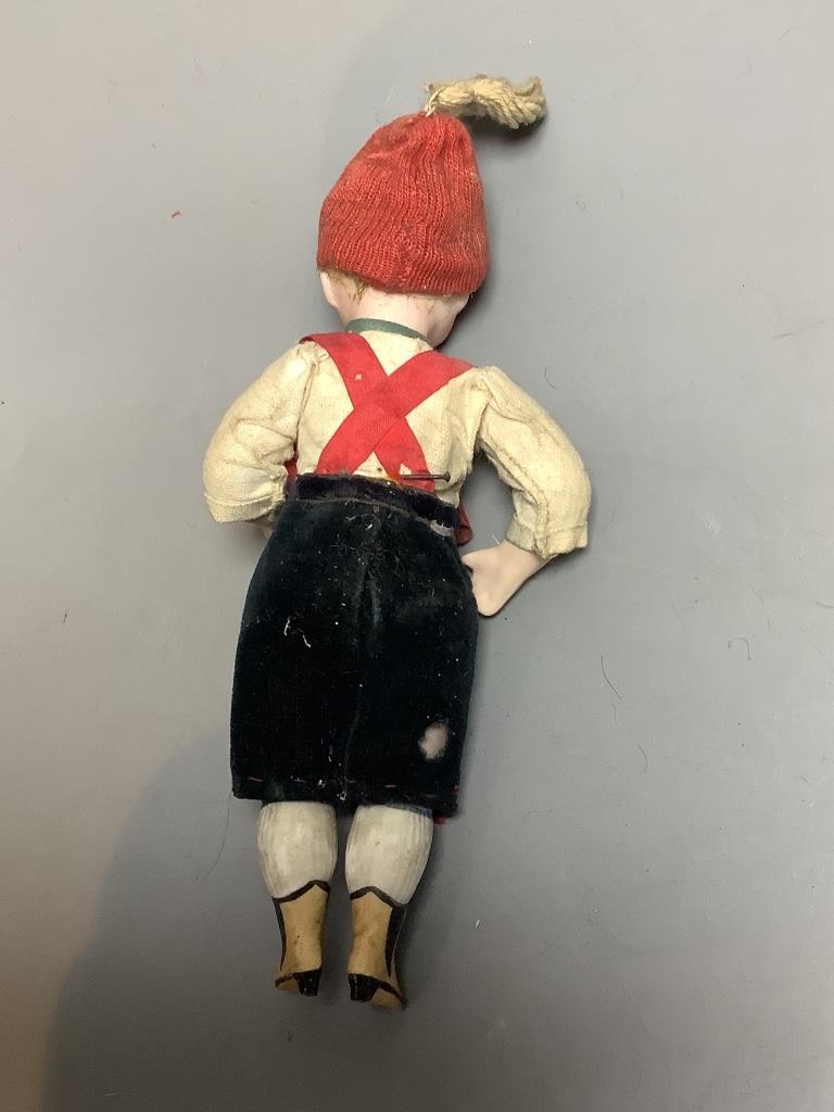 A bisque doll with boots and large glass eyes, height 15cm